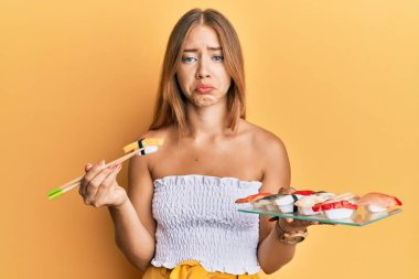 Güzel sarışın kadın yemek çubuklarıyla omlet yiyor. Depresyonda ve üzüntüden ağlıyor. Kızgın ve korkmuş. hüzünlü ifade. 