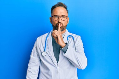 Doktor üniforması ve steteskop giyen yakışıklı orta yaşlı bir adam parmakları dudaklarında sessiz olmak istiyor. sessizlik ve gizli konsept. 