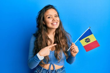 Moldova bayrağı tutan genç İspanyol kız mutlu bir şekilde el ve parmak işareti yapıyor. 