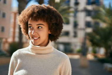 Genç İspanyol kız gülümseyerek şehirde mutlu mesut dikiliyor..