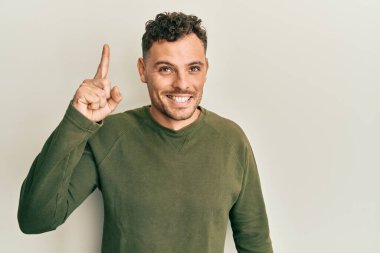 Gündelik kıyafetler giyen genç İspanyol adam başarılı bir fikirle işaret ediyor. Heyecanlı ve mutlu. Bir numara.. 