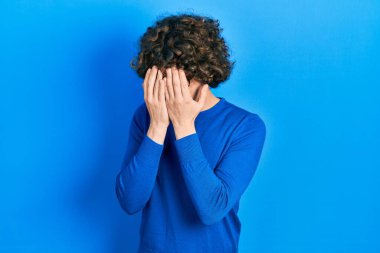 Yakışıklı genç adam gündelik kıyafetler giyiyor ve ağlarken suratını ellerle örten üzgün bir gözlük takıyor. depresyon kavramı. 