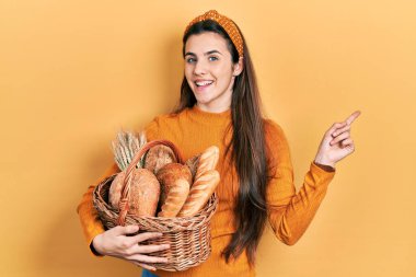 Genç esmer ergen elinde hasırdan sepetle gülümsüyor. 