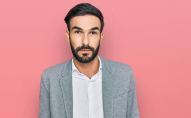 İş kıyafetleri giyen genç İspanyol adam yüzünde ciddi bir ifadeyle rahatladı. Basit ve doğal bir şekilde kameraya bakıyorsun.. 