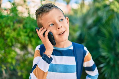 Sevimli beyaz çocuk gülümsüyor. Parktaki akıllı telefondan konuşuyor..