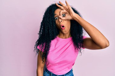 Orta yaşlı Afro-Amerikalı kadın günlük kıyafetler giyiyor. Şaşırmış yüz ve gözlerle parmaklarından bakıyor. İnançsız ifade. 