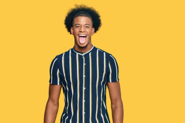 Afro saçlı, sıradan kıyafetler giyen, komik bir ifadeyle dilini dışarı çıkaran Afrikalı Amerikalı bir adam. duygu kavramı. 