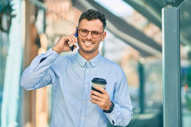 Genç İspanyol işadamı akıllı telefondan konuşuyor ve şehirde kahve içiyor..