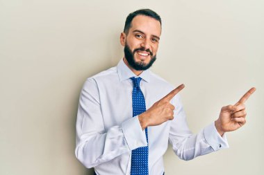 Sakallı, iş kravatı takan, gülümseyen ve kameraya bakan genç bir adam.. 