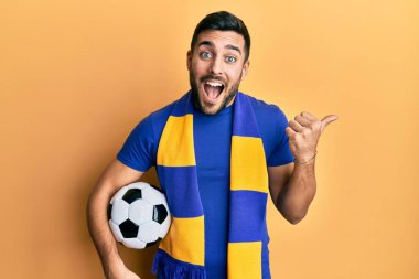 Genç İspanyol futbolcu holigan futbol topu başparmağını yan tarafa uzatıyor ve ağzı açık gülümsüyor. 