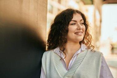 Genç İspanyol kadın gülümseyerek şehirde mutlu mesut dikiliyor..