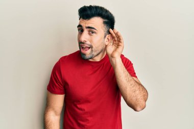 Gündelik kıyafetler giyen, ağzı kulaklarında gülümseyen, dedikoduları ve dedikoduları dinleyen genç İspanyol bir adam. Sağırlık kavramı. 