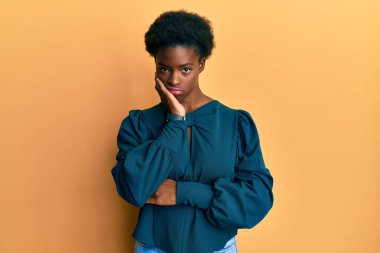 Genç Afro-Amerikalı kız günlük kıyafetler giyip kollarını kavuşturarak depresyondan sıkılmış ve yorgun görünüyor.. 