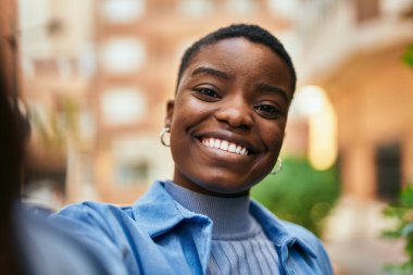 Genç Afrikalı Amerikalı kadın gülümsüyor. Mutlu bir şekilde şehrin kamerasının önünde selfie çekiyor..