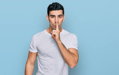 Yakışıklı, beyaz tişört giyen, dudakları dudaklarında sessiz olmak isteyen bir İspanyol. sessizlik ve gizli konsept. 