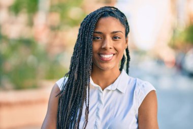 Genç Afrikalı Amerikalı kadın gülümseyerek şehirde mutlu mesut duruyor..