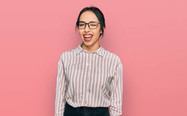 Gündelik kıyafetler giyen ve gözlüklü genç İspanyol kız kameraya seksi bir ifadeyle bakıyor, neşeli ve mutlu bir yüzle.. 