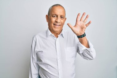 Yakışıklı, beyaz tişört giyen, 5 numarayı gösteren ve gülümseyen, kendinden emin ve mutlu bir adam.. 