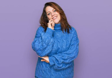 Gündelik kıyafetler giyen genç bir kadın kameraya kendinden emin bakıyor kollarını kavuşturup gülümsüyor ve çenesini kaldırıyor. Olumlu düşünmek. 