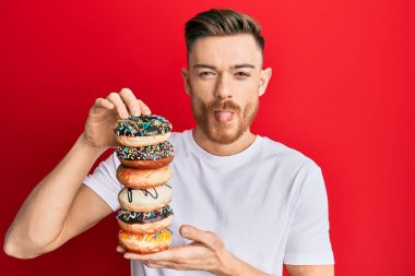 Genç kızıl saçlı adam elinde lezzetli renkli çörekler tutuyordu. Komik bir ifadeyle dilini dışarı çıkarıyordu.. 