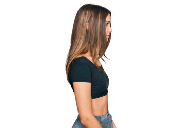 Genç esmer kadın günlük giysiler giyiyor. Yan tarafa bakıyor, rahat poz veriyor. Kendine güvenen bir gülümsemesi var.. 