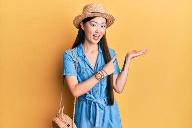 Yazlık şapkalı genç Çinli kadın kameraya hayret ediyor ve gülümsüyor.. 