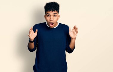 Genç Afro-Amerikan adam günlük giysiler giyiyor. Şaşırmış ve şaşırmış bir ifadeyle, korku ve heyecanlı bir yüzle.. 