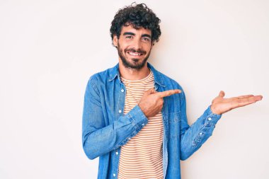 Kıvırcık saçlı ve ayı gibi rahat kot ceket giyen yakışıklı genç adam kameraya hayret ediyor ve gülümsüyor.. 