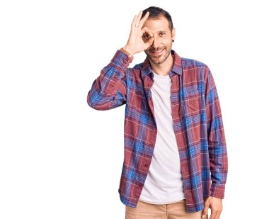 Sıradan kıyafetler giyen genç yakışıklı adam el hareketleriyle gülümsüyor, mutlu yüzüyle parmaklarının arasından bakıyor.. 