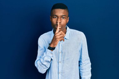 Gündelik giysiler giymiş genç Afro-Amerikan bir adam sessiz olmak istiyor. sessizlik ve gizli konsept. 