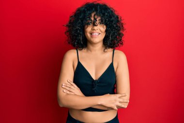 Kolsuz tişörtlü, mutlu yüzlü, kollarını kavuşturup kameraya bakan İspanyol bir kadın. pozitif kişi. 