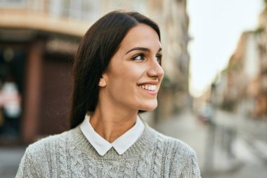 Genç İspanyol kadın gülümseyerek şehirde mutlu mesut dikiliyor..