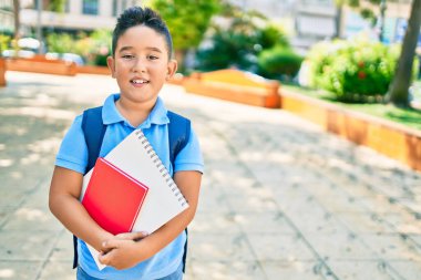 Sevimli öğrenci gülümsüyor. Şehrin caddesinde kitap tutarken mutlu..