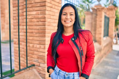 Genç Latin kadın gülümseyerek şehirde mutlu mesut yürüyor..