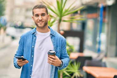 Kafkasyalı genç adam akıllı telefon kullanıyor. Şehirde kahve içiyor..