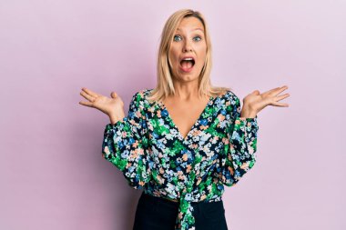 Orta yaşlı beyaz kadın gündelik giysiler giyip zaferi mutlu bir gülümsemeyle kutluyor ve kazanan el kaldırarak ifade ediyor. 