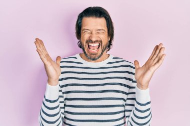 Orta yaşlı beyaz bir adam, sıradan kıyafetler giyip başarıyı kutluyor. Kolları havada, gözleri kapalı, heyecanlı bir şekilde bağırıyor. Kazanan konsept 