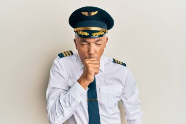 Yakışıklı, olgun, uçak pilotu üniforması giyen kendini iyi hissetmeyen ve soğuk algınlığı veya bronşitin belirtisi olarak öksüren bir adam. sağlık hizmeti kavramı. 