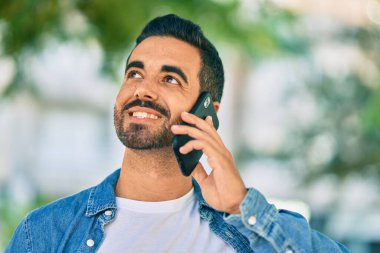 Genç İspanyol adam gülümsüyor. Parktaki akıllı telefondan konuşarak mutlu oluyor.