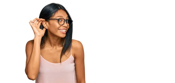 噂やゴシップに耳を傾ける耳の上に手で笑みを浮かべてカジュアルな服や眼鏡を着用若いアフリカ系アメリカ人女性 聴覚障害の概念 — ストック写真