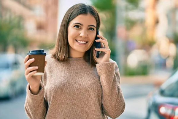 若いヒスパニック系の女性が街のスマートフォンのコーヒーを飲む話 — ストック写真