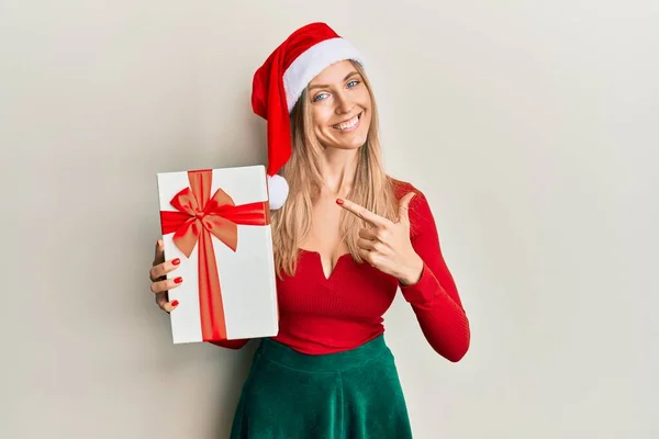 美しいCaucasian女性身に着けているクリスマスの帽子と開催ギフト笑顔幸せなポインティングで手と指 — ストック写真