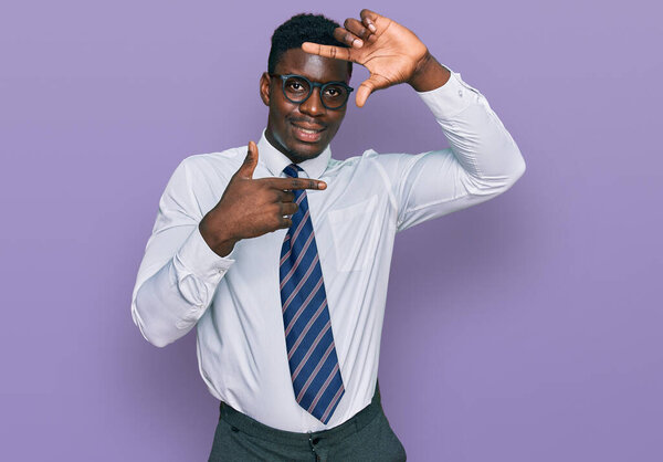 Handsome business black man wearing white shirt and tie smiling making frame with hands and fingers with happy face. creativity and photography concept.