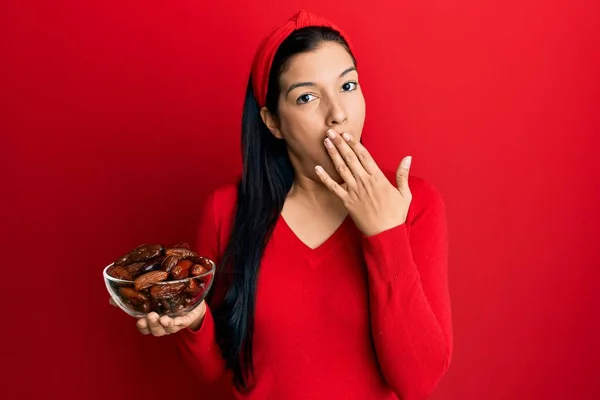 年轻的拉丁女人拿着碗 手上捂着红枣嘴 既震惊又害怕犯错 惊讶的表情 — 图库照片