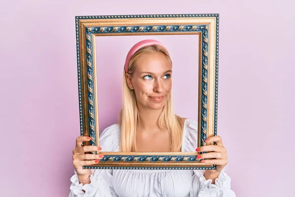 Young Blonde Girl Holding Empty Frame Smiling Looking Side Staring — ストック写真