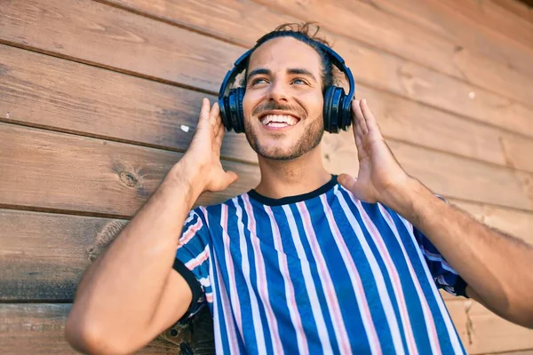 若いヒスパニック系の男は 市内でヘッドフォンを使用して音楽を聞いて幸せな笑顔 — ストック写真