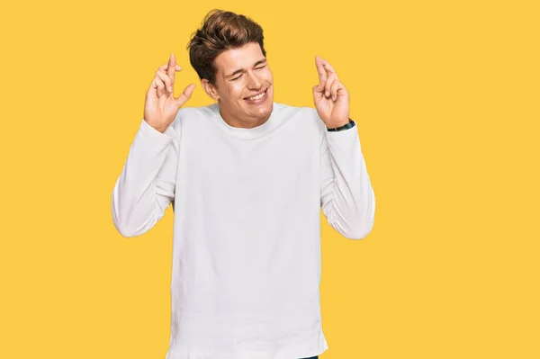 Handsome Caucasian Man Wearing Casual White Sweater Gesturing Finger Crossed — Stock Photo, Image