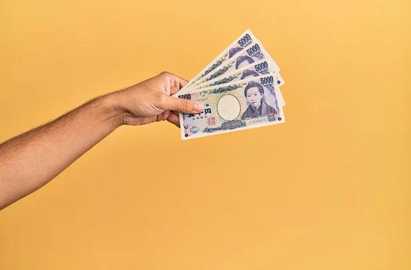 在孤立的黄色背景下手握日元钞票的惊慌失措的人 — 图库照片