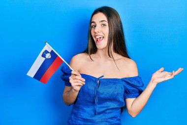 Slovenia bayrağı taşıyan genç esmer kız başarıyı mutlu bir gülümsemeyle kutluyor ve kazanan yüz ifadesi kaldırıyor. 