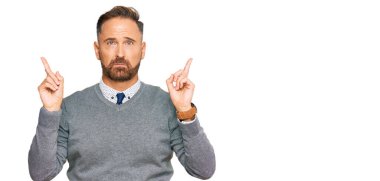 Handsome middle age man wearing business clothes pointing up looking sad and upset, indicating direction with fingers, unhappy and depressed. 